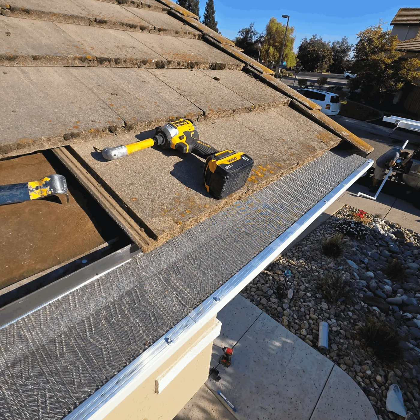 Drill and micro-mesh gutter guard on a Sacramento-area roofline mid-installation