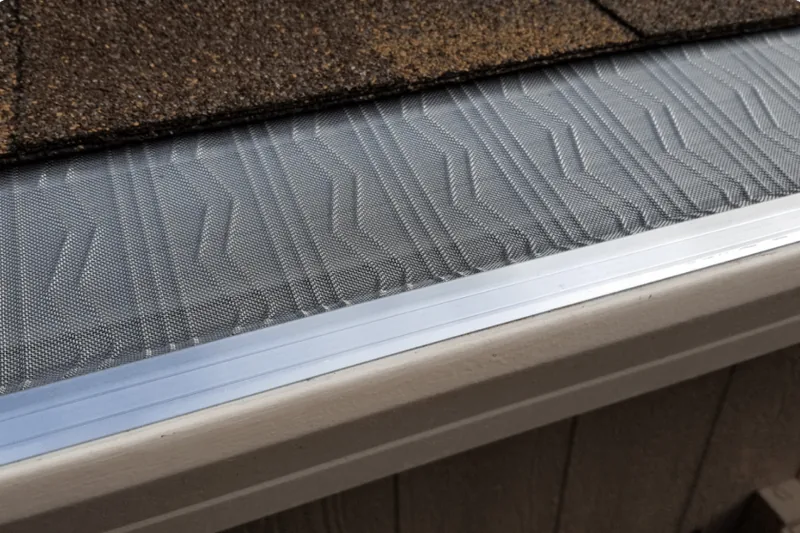 LeafBlaster Pro stainless micro-mesh gutter guard installed beneath brown roof shingles